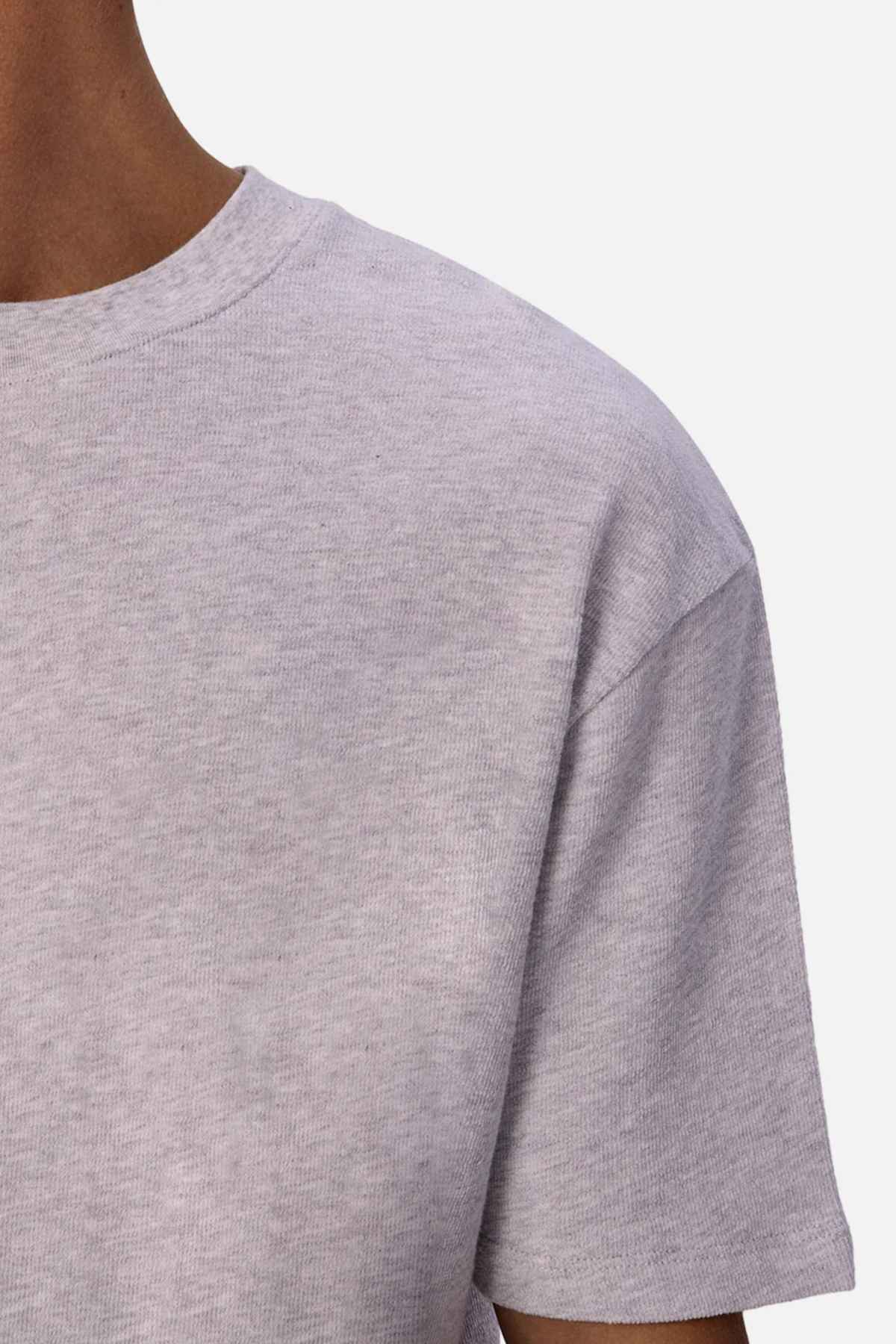 Close-up of a person wearing a light gray Industrie The Henderson Boucle Tee against a plain background. The image focuses on the shoulder and upper chest area, highlighting the 100% cotton fabric texture and hinting at an oversized look.