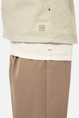 A person wears the Industrie The Huntsville Jacket over a white shirt with brown trousers, showcasing the classic collar, layered clothing, and minimalistic style with small visible labels.