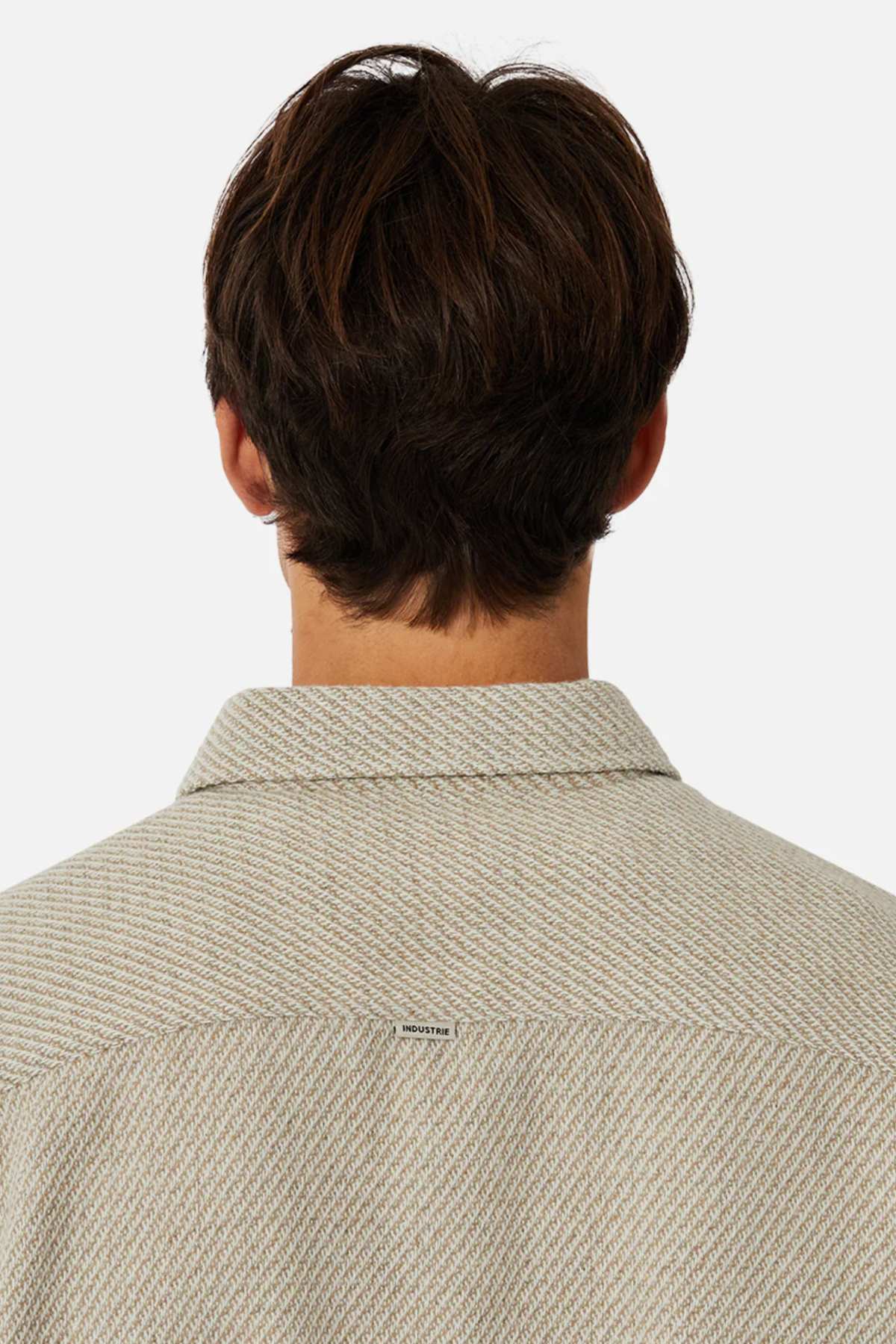 Rear view of a person with brown hair wearing a stylish Industrie The Jackson Shirt, featuring a light texture. Its relaxed fit prioritizes comfort, focusing on the upper back and collar against a white background.