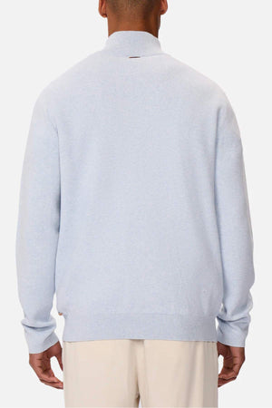 Someone wearing the Industrie The Lakewood Zip Neck, a light gray regular fit sweater, and cream-colored pants is seen from the back against a plain white background. The cotton jumper has a simple design with ribbed collar, cuffs, and hem.