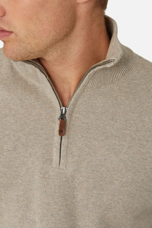 Close-up of a person wearing the Industrie The Lakewood Zip Neck, light beige cotton jumper in regular fit, featuring a ribbed collar and brown zip pull. The person's head is turned to the side against a white background.