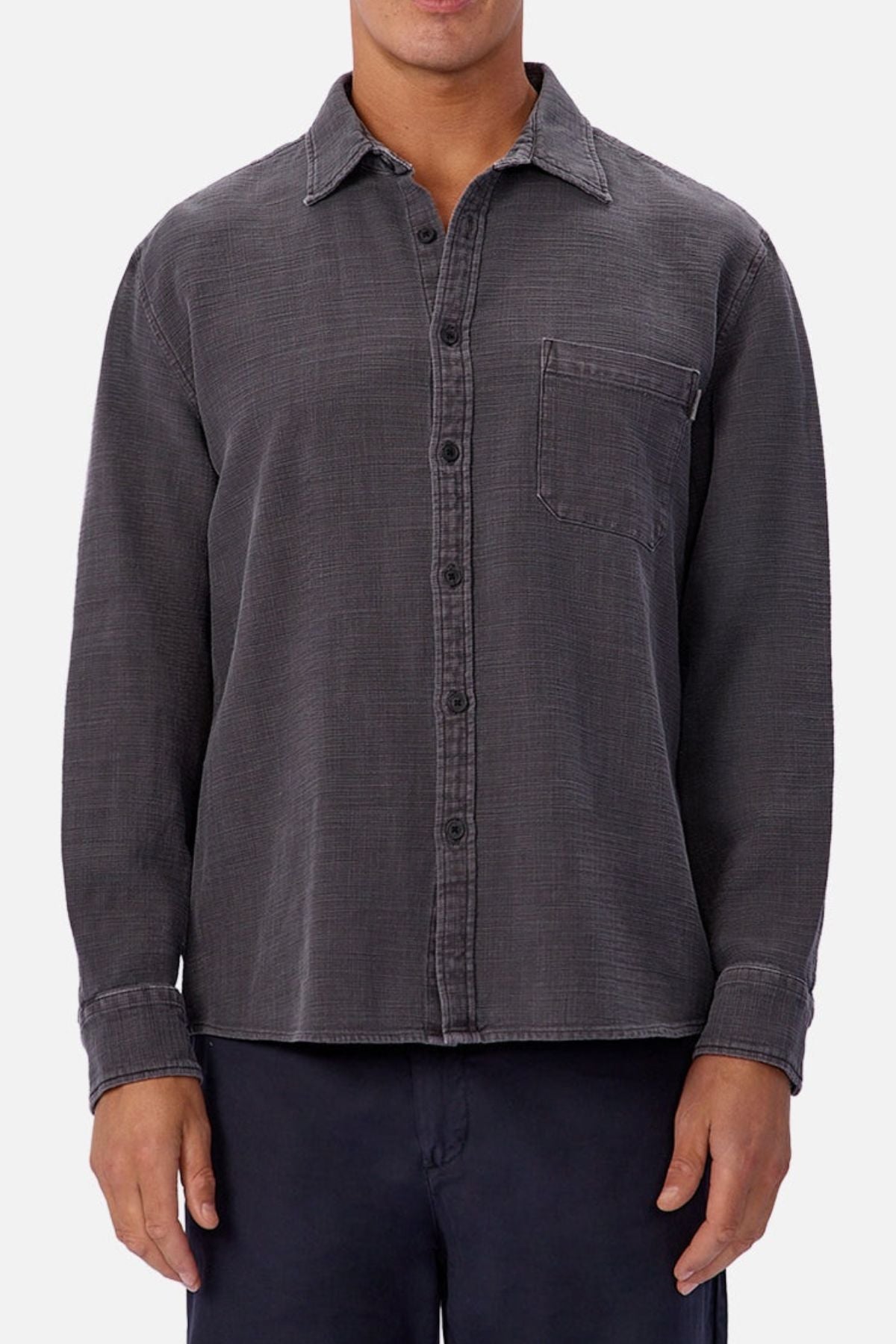 Someone wearing the Industrie Lisbon Long Sleeve Shirt—a dark gray, 100% cotton, textured long-sleeve button-up with classic collar and chest pocket—paired with dark pants, stands against a plain light background.