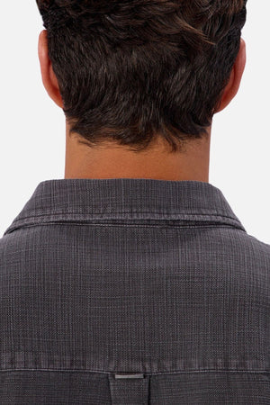 The image shows the back of a person with short brown hair, wearing the Industrie Lisbon Long Sleeve Shirt in textured dark gray 100% cotton with a classic collar, set against a light background.