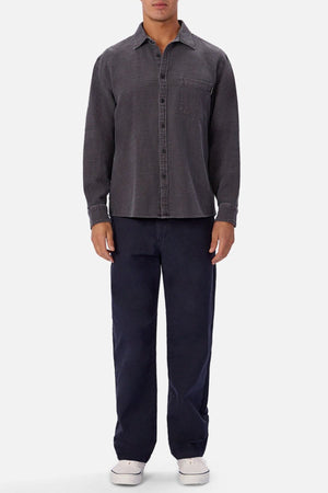 A man stands facing forward wearing the Industrie Lisbon Long Sleeve Shirt in dark grey, navy blue pants, and white sneakers against a plain light background.
