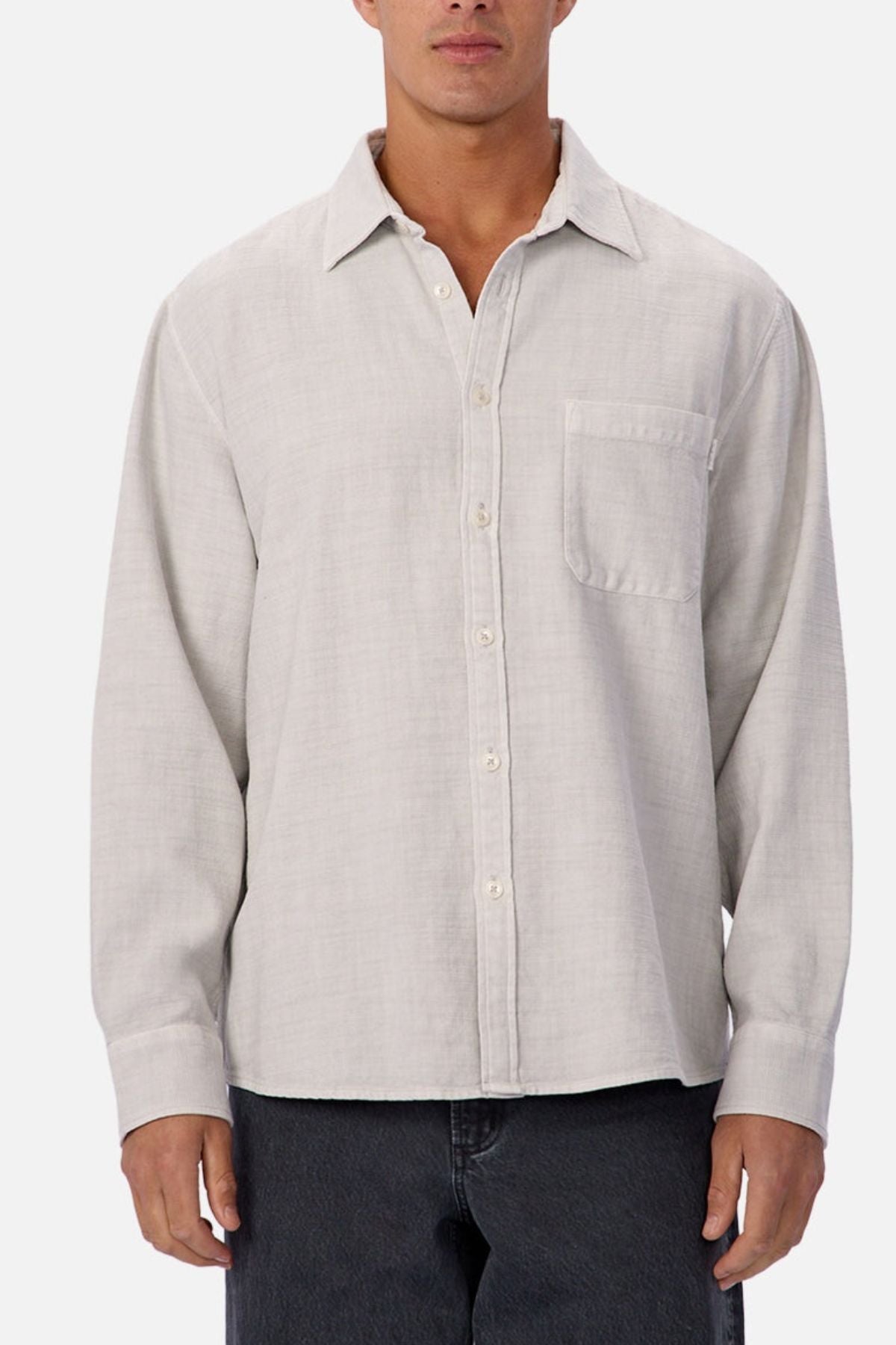 A person wears the Industrie Lisbon Long Sleeve Shirt in light gray, made from 100% cotton with a chest pocket and classic collar, untucked over dark pants against a plain background.