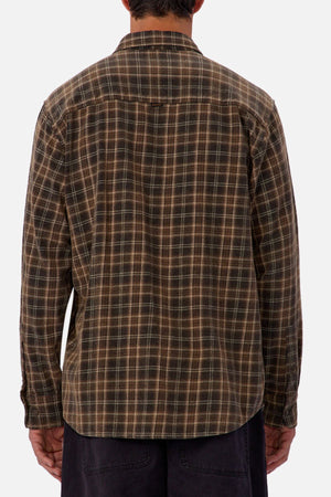A person stands with their back to the camera wearing the Industrie The Maple Long Sleeve Shirt, which features brown and beige checks, paired with dark pants against a plain background.