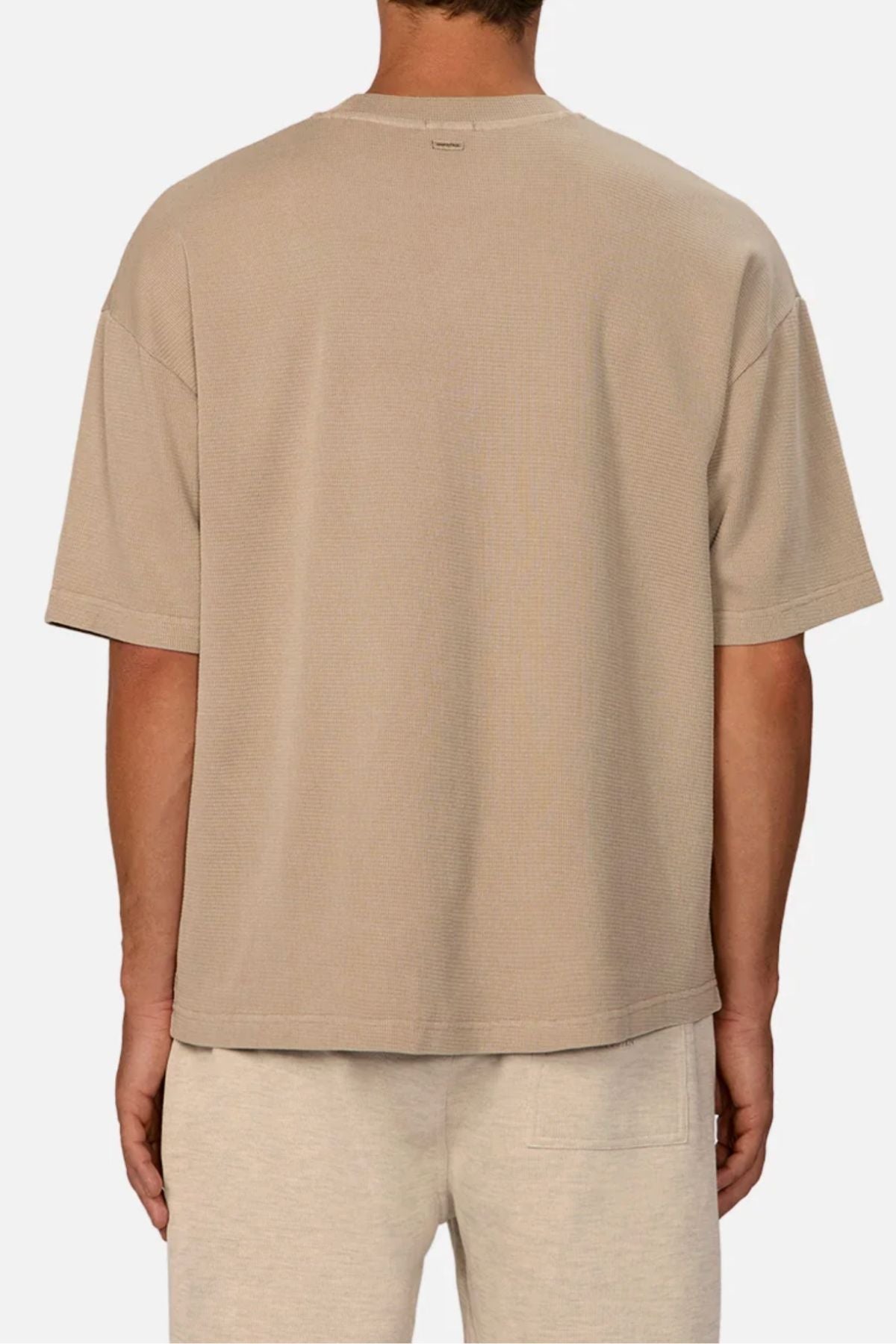 A person is seen from the back against a plain light background, wearing the Industrie The Marlon Tee in beige and light beige shorts—an effortlessly stylish choice for casual wear.
