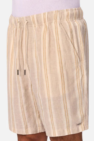 A person wears the Industrie The Matias Short—beige linen shorts with vertical cream and tan stripes, elastic waistband, drawstring, and side pockets. The breathable fabric is ideal for casual everyday wear.