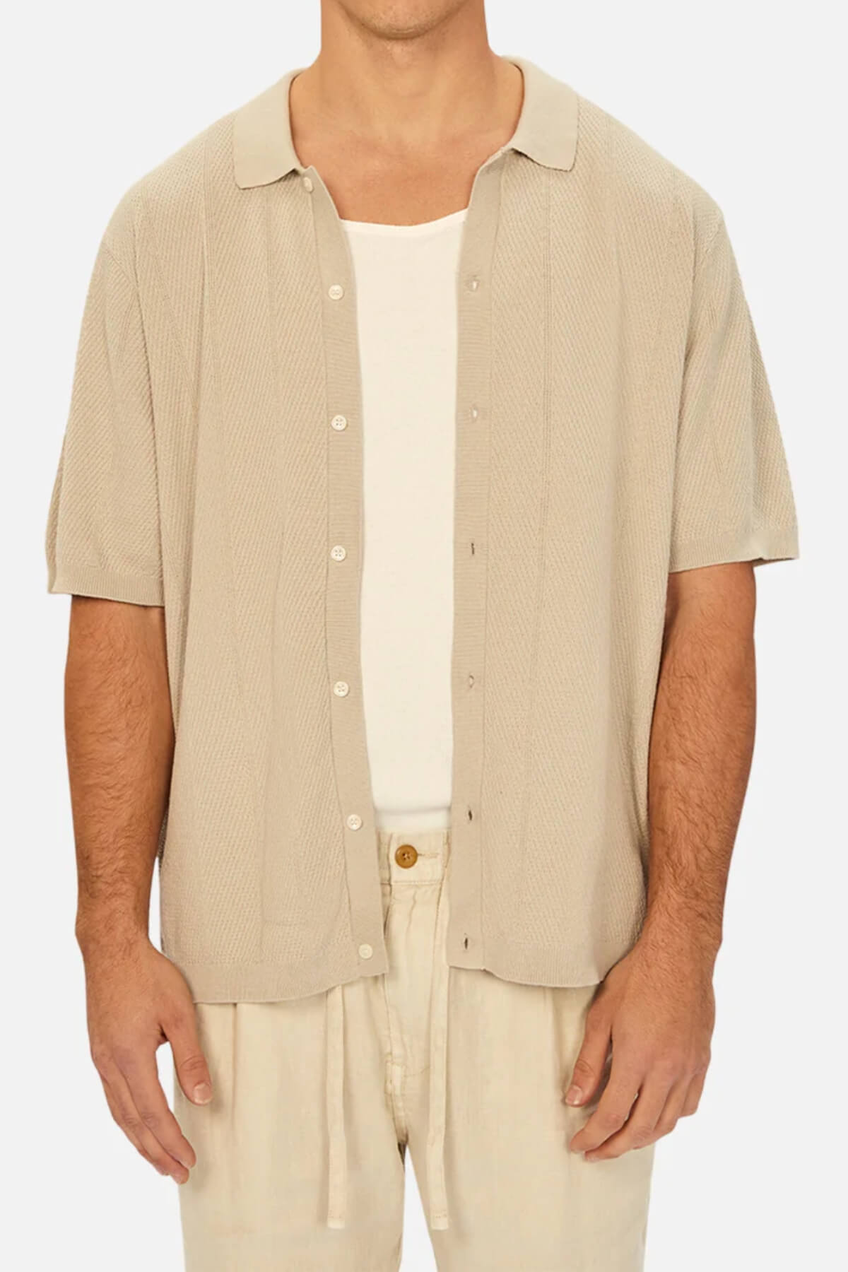 A man wearing the Industrie The Modena Short Sleeve Shirt in beige over a white tank top, paired with beige pants.