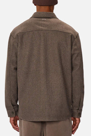 A person is shown from the back wearing the Industrie The New Coleman Jacket, a brown wool jacket with a classic collar, relaxed fit, long sleeves, and buttoned cuffs against a plain white background.