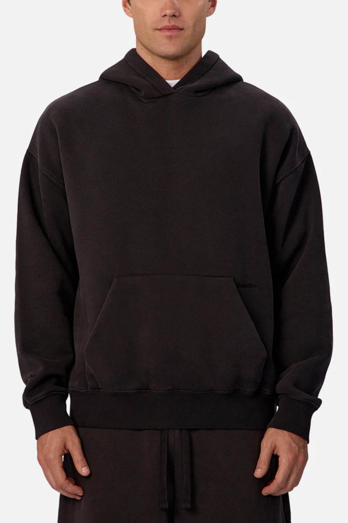 Someone stands against a plain light background, wearing the Industrie The New Del Sur Fleece Hoodie in black. This oversized fleece features long sleeves, a hood, front kangaroo pocket, and a relaxed fit for casual comfort.