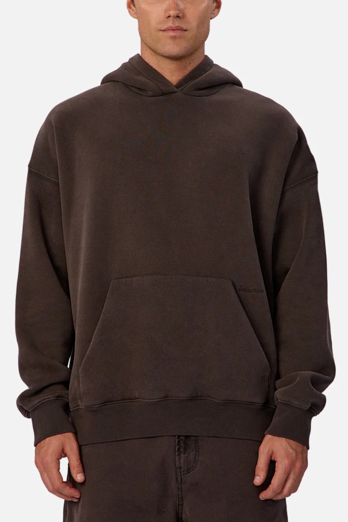 A man wears the Industrie The New Del Sur Fleece Hoodie in dark brown, featuring a relaxed fit, long sleeves, front pocket, and cotton-polyester fleece. His hands are by his sides against a plain white background.