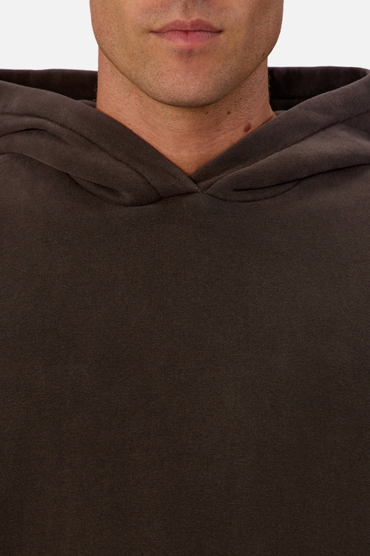 A close-up shows someone wearing the Industrie The New Del Sur Fleece Hoodie in dark brown, with only their lower face and upper chest visible. The hood rests on their shoulders against a plain background.