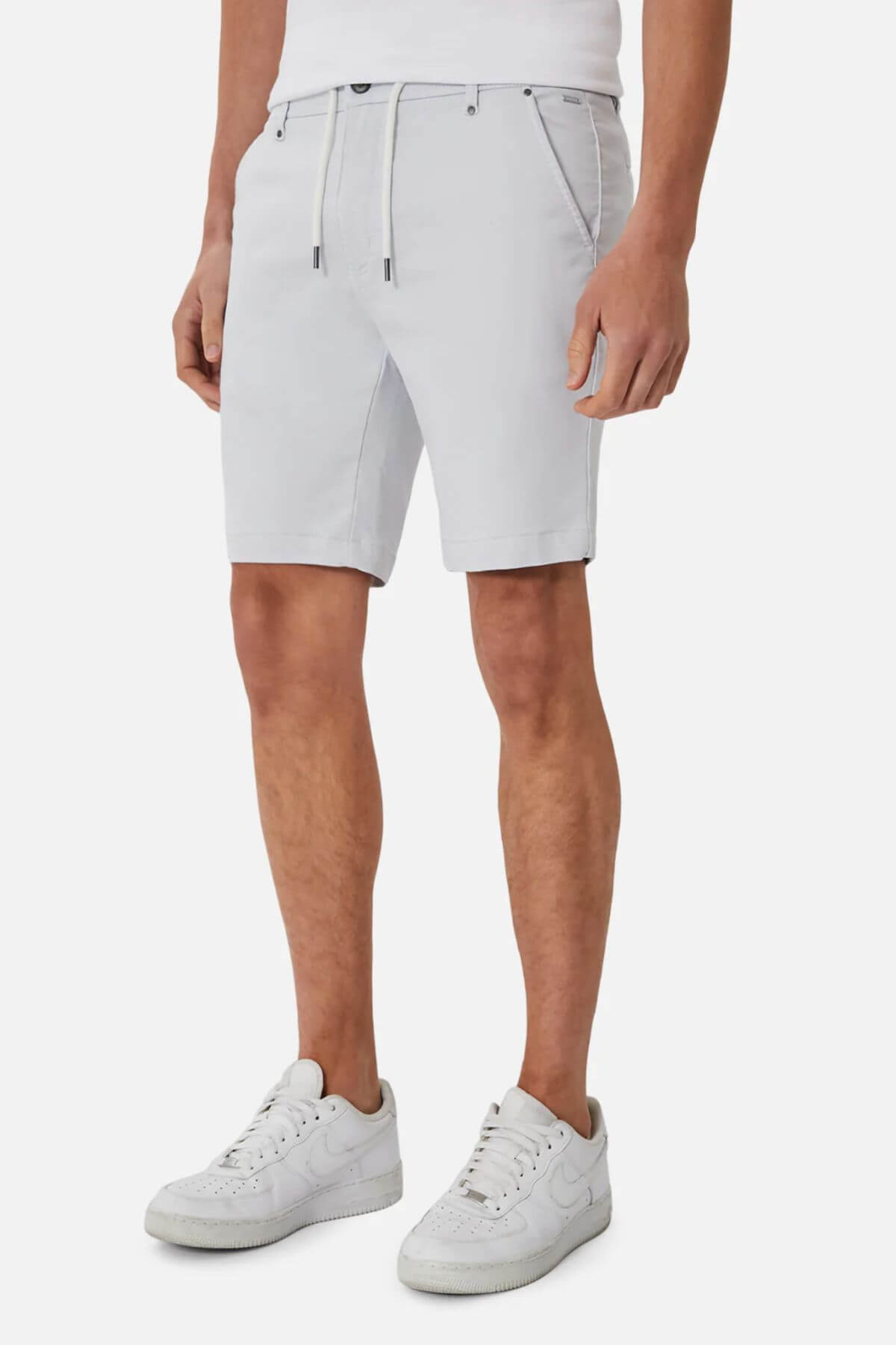 A person models the Industrie The New Drifter Cuba Short in light gray, featuring a slim fit, front pockets, and a drawstring. Paired with white sneakers and shirt, only the lower torso and legs are shown, emphasizing comfortable style.
