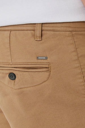 Close-up of the back of tan Industrie The New Drifter Cuba Short, featuring a black pocket button and metallic "INDUSTRY" label above, paired with a tucked-in white shirt for a casual, stylish look.