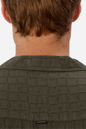 Seen from behind, a person with short brown hair is wearing the Industrie The New Ortigia Short Sleeve Shirt in a dark green jacquard pattern. The camp collar provides a hint of casual elegance, and the shirt features an "INDUSTRIE" label.