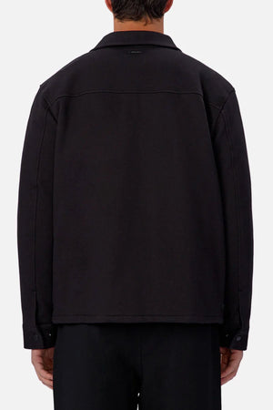 A person is seen from behind wearing the Industrie The New Westport Jacket in black with matching pants. The loose, long-sleeve smart-casual jacket contrasts against a plain light background.