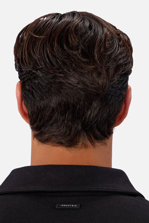A close-up of the back of a person’s head and neck with short, dark, wavy hair. They are wearing the Industrie The New Westport Jacket in black, featuring a small "INDUSTRIE" tag at the back of the collar.