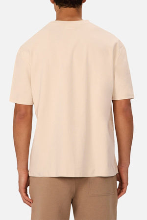 A person is shown from the back wearing the Industrie The Newport Tee in beige and light brown pants, set against a white background.
