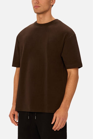 A man wearing the Industrie The Newport Tee and black pants stands against a white background, his face partially out of frame with a neutral expression.