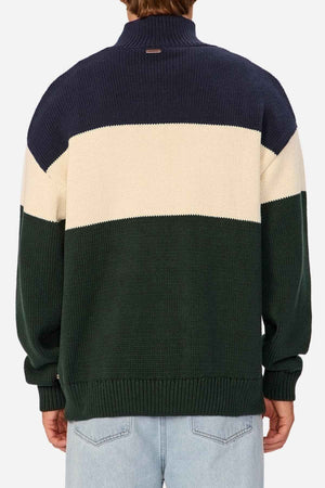 Rear view of a person wearing the Industrie The Osbourne Zip Neck Knit, a timeless piece adorned with navy blue, white, and green horizontal stripes. This 100% cotton sweater features a ribbed texture, long sleeves, and a high collar. The person is also sporting light blue jeans.