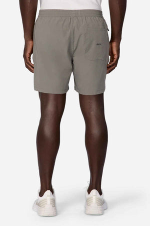 A person is seen from the back wearing Industrie The Owens Short, gray athletic shorts with an elasticized waistband and white sneakers. These above-knee-length shorts have a small pocket on one side and are made of quick-drying fabric against a plain white background.