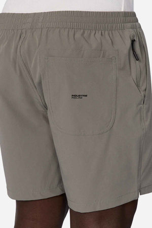 A person is wearing Industrie The Owens Short in light olive green, featuring an elasticized waistband and quick-drying fabric. The back pocket showcases a small black "INDUSTRIE INCLINE" logo. These above-knee-length shorts are perfectly paired with a crisp white shirt.