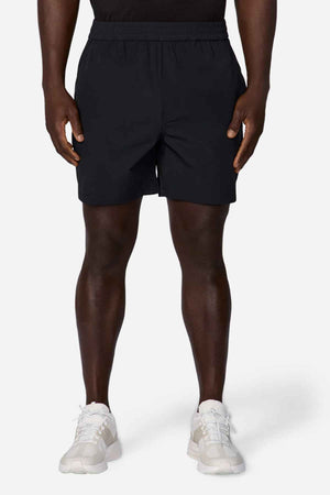 A person wearing a black T-shirt, Industrie The Owens Shorts featuring an elasticised waistband, and white sneakers stands against a plain white background. Only the lower part of their body is visible, showcasing the clothing and shoes.