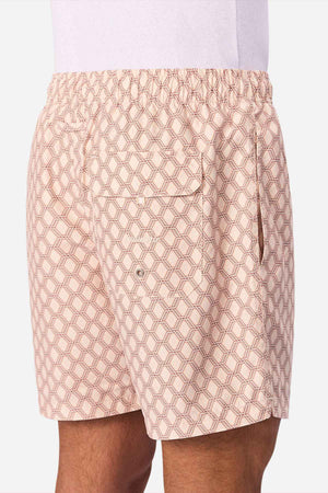 A person wears Industrie The Panama Swim Short in light pink with patterns, featuring an elastic waistband, back pocket with grommet, and side pocket. A white shirt is partly visible, highlighting these stylish men's swim shorts.