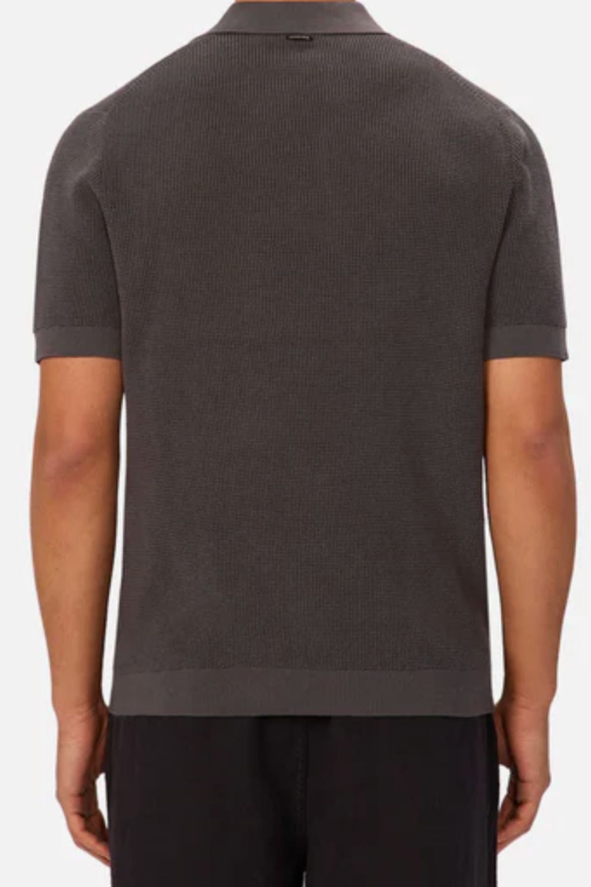 A person is shown from the back wearing the Industrie The Ravenna Polo in dark gray with a subtle waffle knit and straight hem, paired with black pants, set against a plain white background.