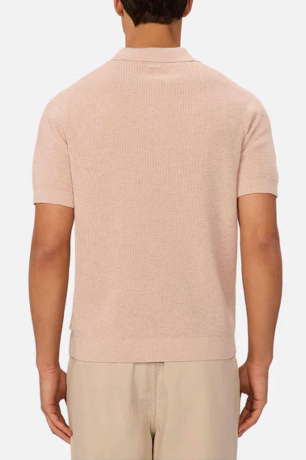 A man is shown from the back wearing an Industrie The Ravenna Polo, a short-sleeve light pink cotton shirt, paired with beige pants against a plain white background.