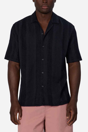 The individual exudes effortless style in an Industrie The Salamanca Short Sleeve Shirt, made from a cotton-linen blend featuring a subtle striped pattern. Teamed with light pink pants, this outfit is ideal for enhancing any summer wardrobe against the clean simplicity of a white setting.