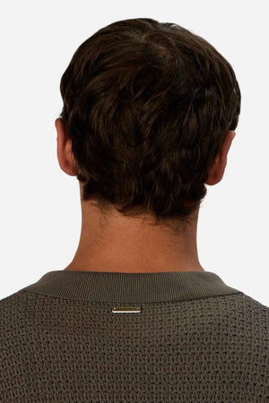 Back view of a person with short brown hair, wearing the Industrie The Sevona Short Sleeve Shirt. A small metallic label embellishes the upper back, subtly indicating Sevona's touch. The plain light background perfectly complements this stylish summer wardrobe essential.