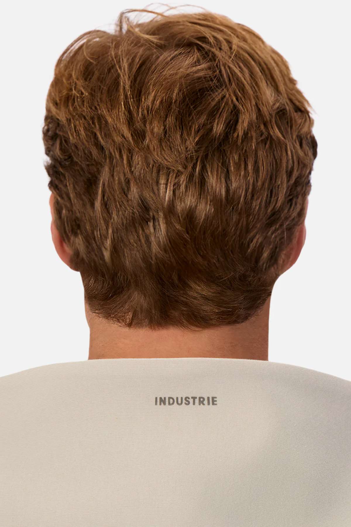A person with short, light brown hair is shown from behind, wearing the Industrie The Tech Del Sur Hood with its logo at the upper back. A plain white background highlights the modern style and athletic design of this light-colored hoodie.