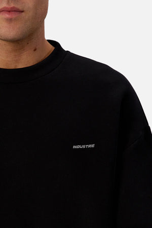 Someone wears the Industrie The Tech Del Sur Sweat, featuring small white "INDUSTRIE" lettering on the chest. Only the lower face and upper body are visible against a plain background.