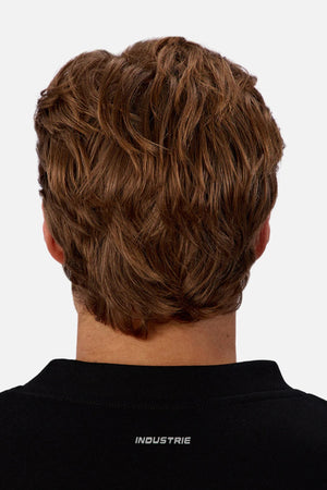 A person with short, wavy light brown hair is seen from the back, wearing the black Industrie The Tech Del Sur Sweat featuring "INDUSTRIE" in white on the collar.
