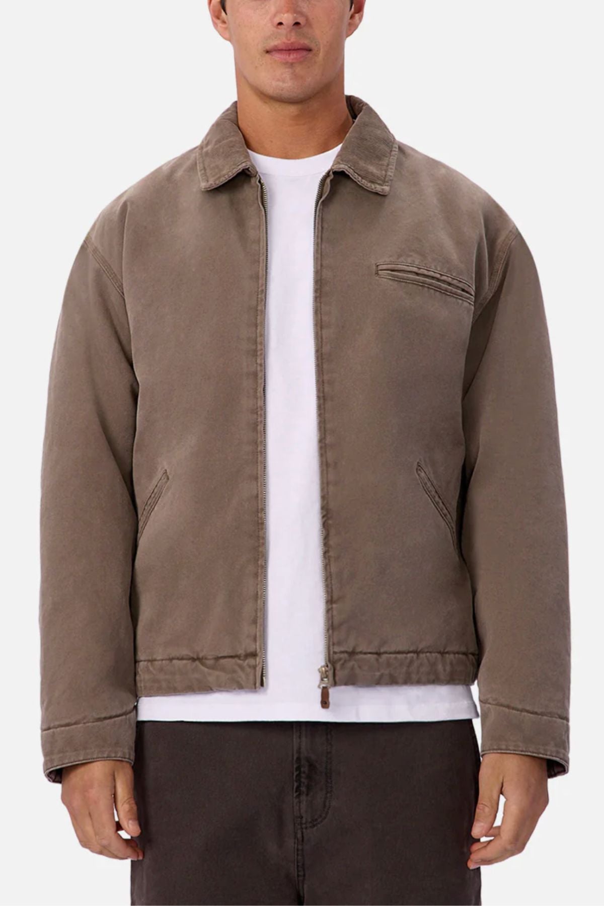 A man wears the Industrie The Tennesse Jacket, a light brown cotton jacket with a collar and two side pockets, over a white t-shirt and dark pants, standing against a plain white background.