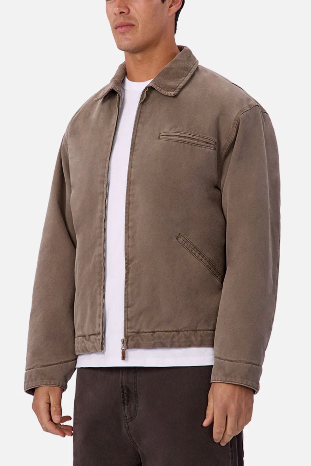 A man wearing the Industrie The Tennesse Jacket in light brown cotton with a collar, styled with a white T-shirt and dark pants, stands against a plain white background.