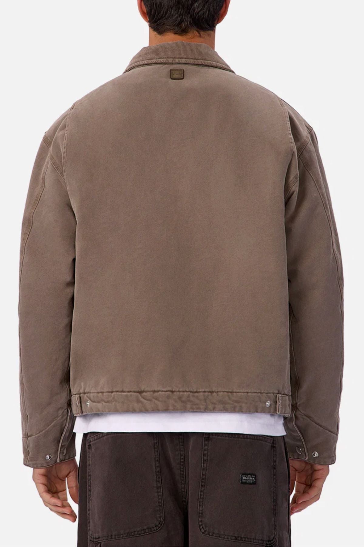 A person is seen from behind wearing the Industrie The Tennesse Jacket in taupe over a white shirt and brown pants. This men’s jacket features a relaxed fit with visible seams plus button details on the cuffs and waistband.