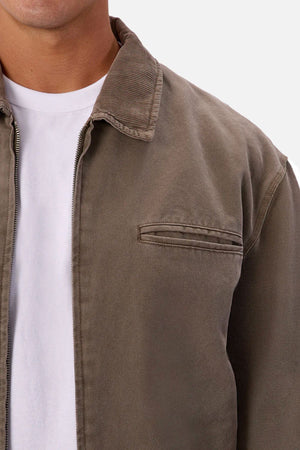 A person models the Industrie The Tennesse Jacket in light brown with a corduroy collar over a plain white t-shirt. Only their lower face and upper torso are shown against a simple background.