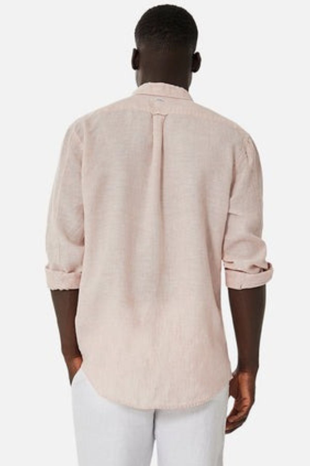 From behind, a person with short hair wears the Industrie The Tennyson Linen Blend Shirt in light pink, highlighting its breezy design. The rolled-up sleeves offer a hint of casual adaptability, perfectly complementing crisp white pants against a simple white background.