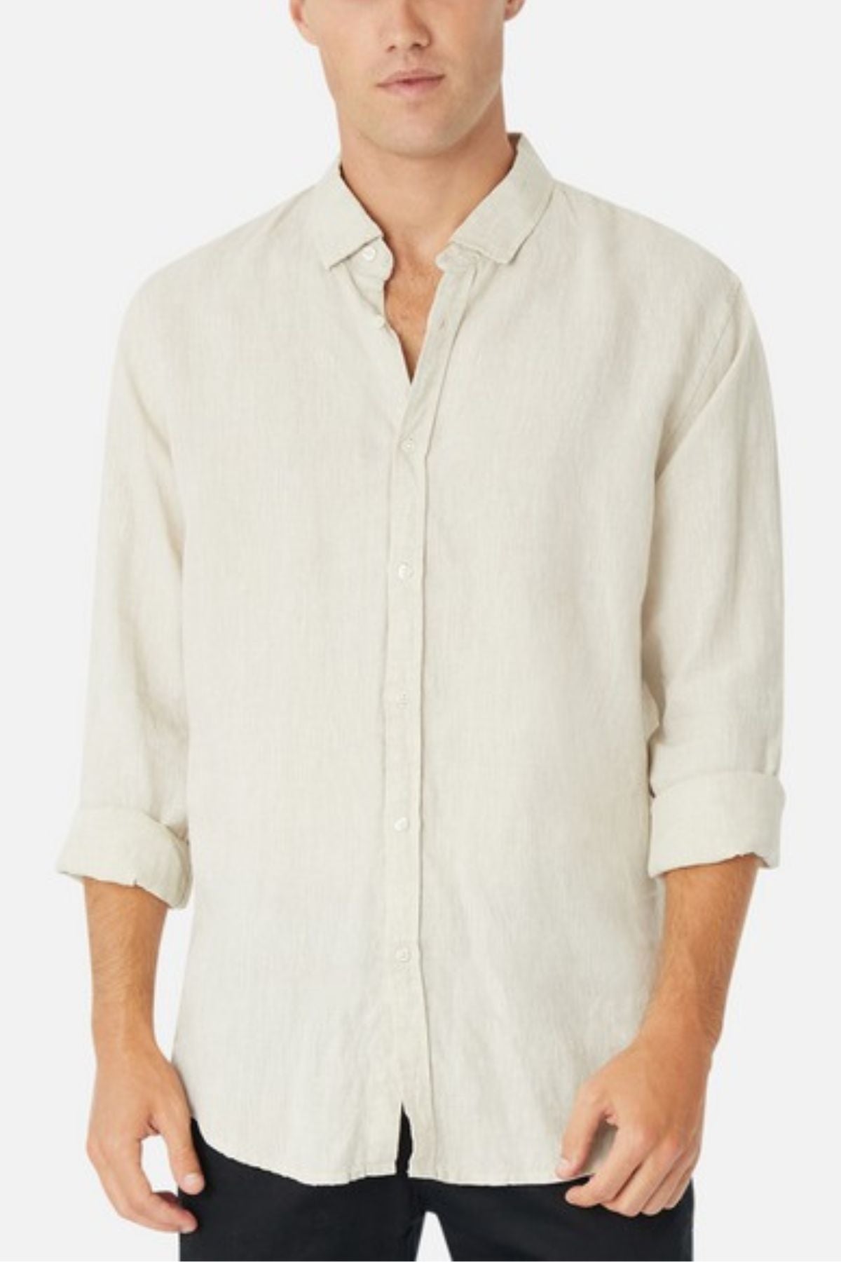 A person wearing the Industrie The Tennyson Linen Blend Shirt in beige, featuring long sleeves with a spread collar and rolled-up cuffs, paired with black pants. The look is perfect for summertime against a plain white background.