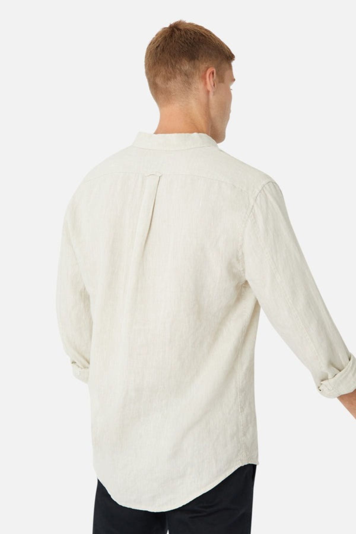A person with short hair is wearing the Industrie The Tennyson Linen Blend Shirt in light beige, which has a spread collar. Seen from the back, the sleeves are stylishly rolled up to the elbows, creating a breezy summertime vibe. The shirt is untucked over black pants against a plain white background.