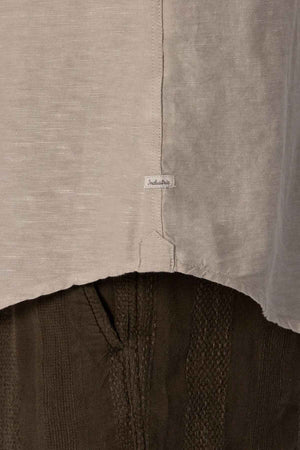 Close-up of a gray fabric with a small tag reading "Indelible," above dark textured pants. The image highlights the clothing materials and stitching details, reminiscent of a finely crafted Industrie The Tennyson Linen Blend Shirt, perfect for those breezy days.