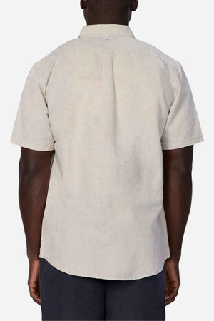 A person is shown from the back wearing the Industrie The Tennyson Linen Blend Short Sleeve Shirt in light beige. This versatile shirt features a collar and simple, plain design, providing ideal summertime comfort against a plain white background.