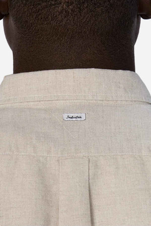 Close-up of the back of a person's neck and shoulders, wearing the Industrie The Tennyson Linen Blend Short Sleeve Shirt in light beige, which exudes summertime comfort, with a small label reading "Industrie.