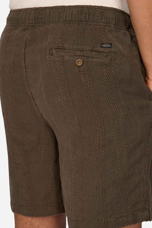 A person wearing green Industrie The Washed Salamanca Short, made from a textured cotton blend with an elastic waistband and a single back pocket, stands against a plain background.