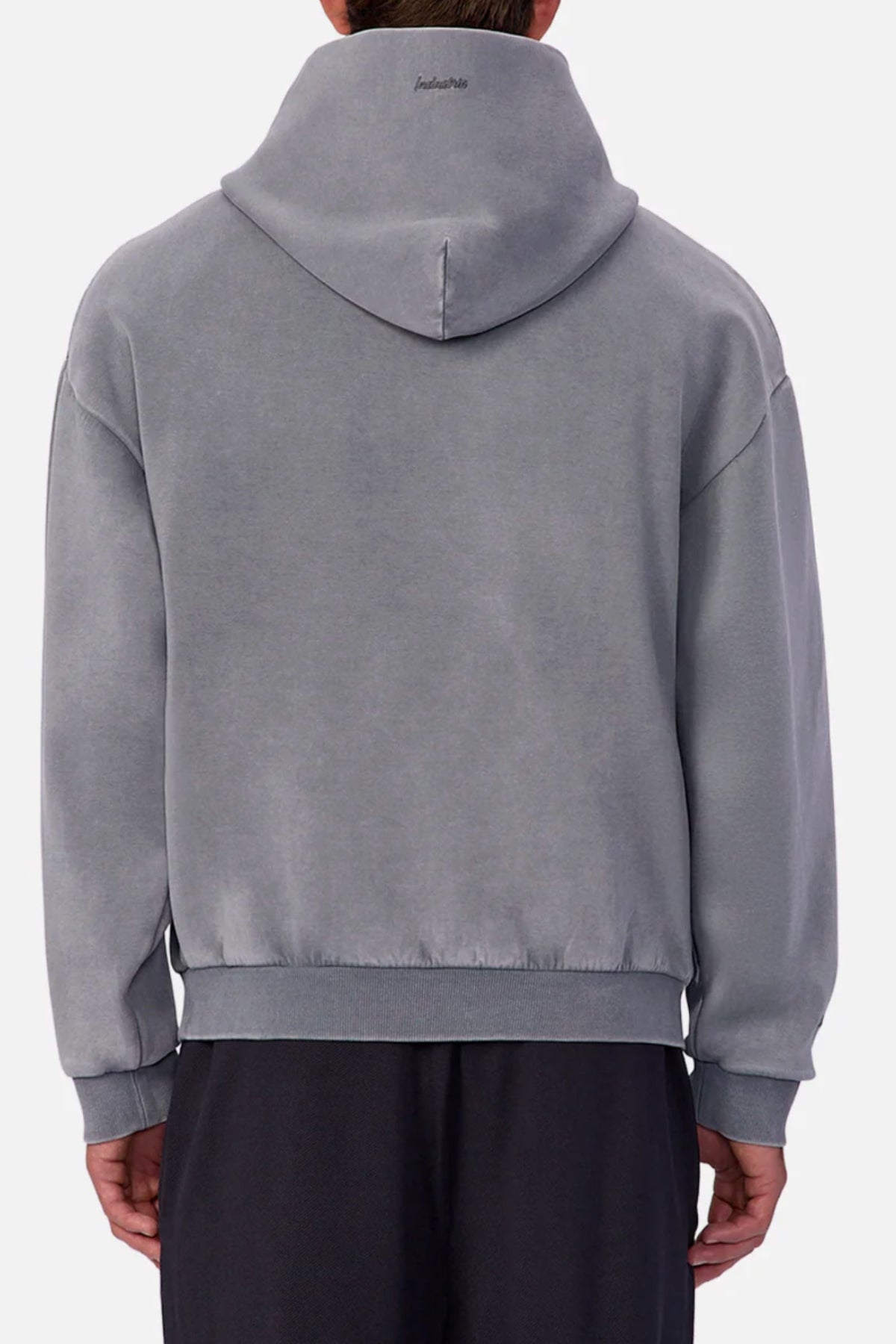 Someone wearing the Industrie The Washed Tech Hood—a loose-fitting, light gray sweatshirt—paired with dark pants, shown from the back against a plain light background. Perfect as a casual layering piece.