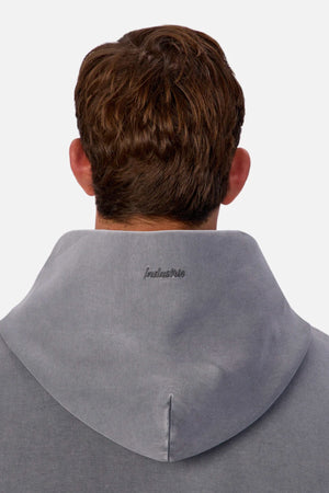 A person with short brown hair is seen from behind wearing the Industrie The Washed Tech Hood in gray, featuring "inclusive" embroidered on the back, merging casual comfort with modern style.
