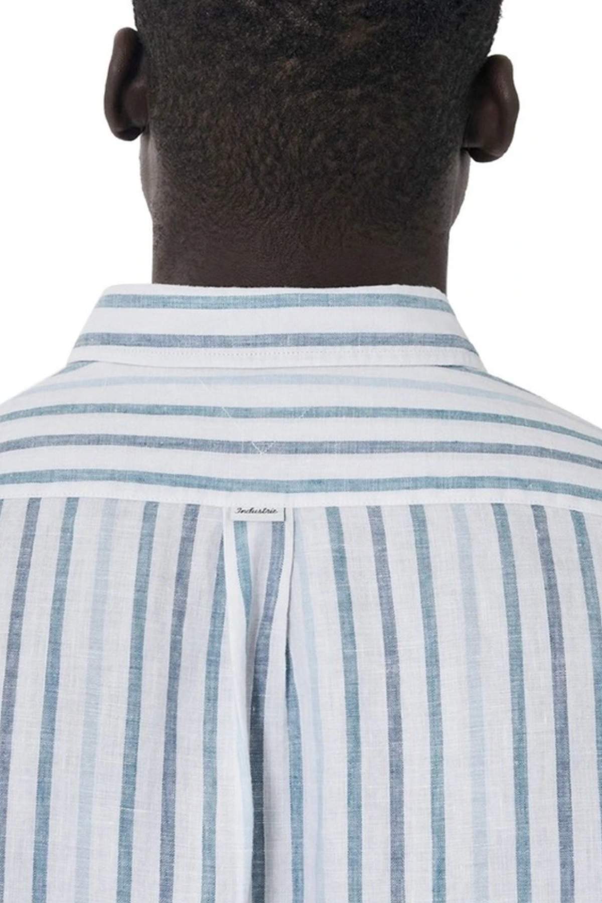 Back view of a person wearing the Industrie The Webster Long Sleeve Shirt in light blue and white vertical stripes. Featuring a relaxed fit, button-down collar with horizontal stripes, and a small label on the upper back.